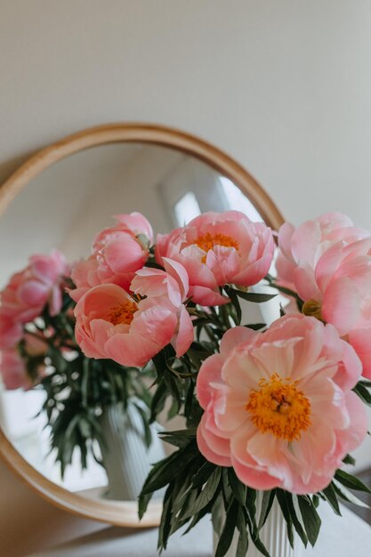 A vase of pink flowers sits on a mirror.