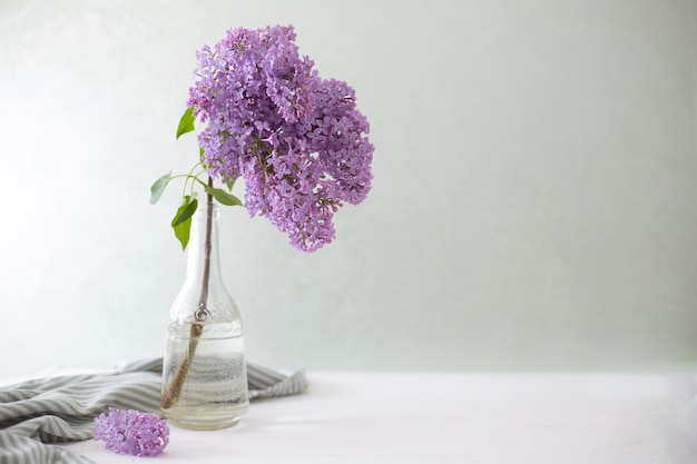 紫色の花が入った花瓶がテーブルの上にあり、縞模様のタオルが置かれています。