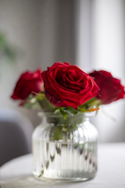 A vase of red roses sits on a table.