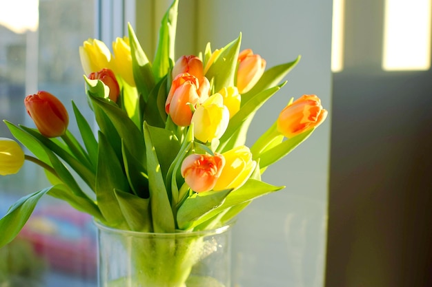 A vase of tulips is sitting on a window sill.