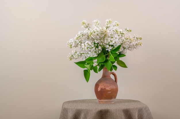 A vase of white lilac flowers on a table