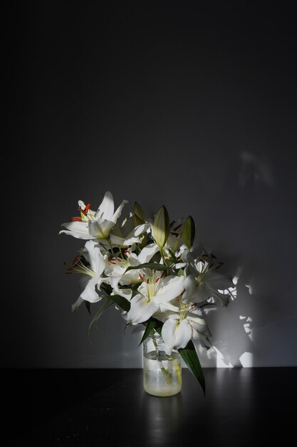 A vase of white lilies with the sun shining on it