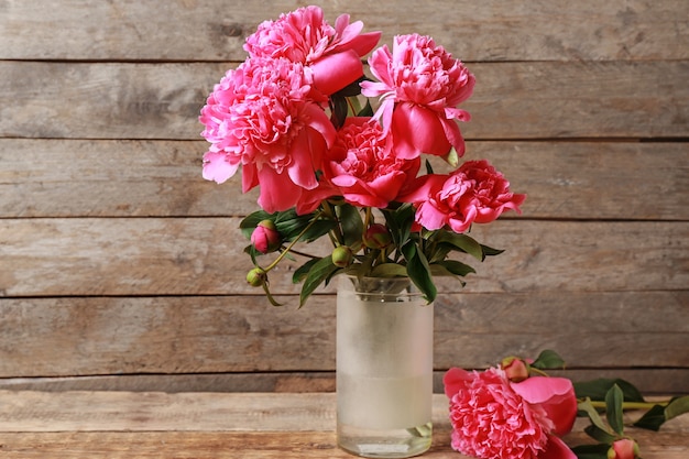 Vase with beautiful peonies on wooden table