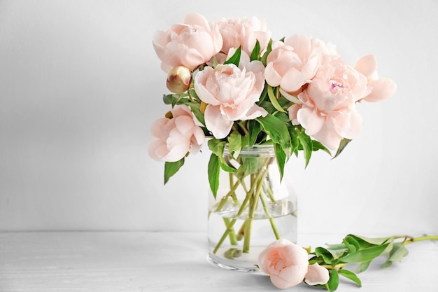 Vase with beautiful peony flowers on table