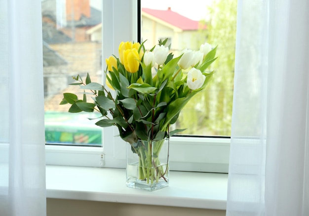 Vase with beautiful tulips on windowsill