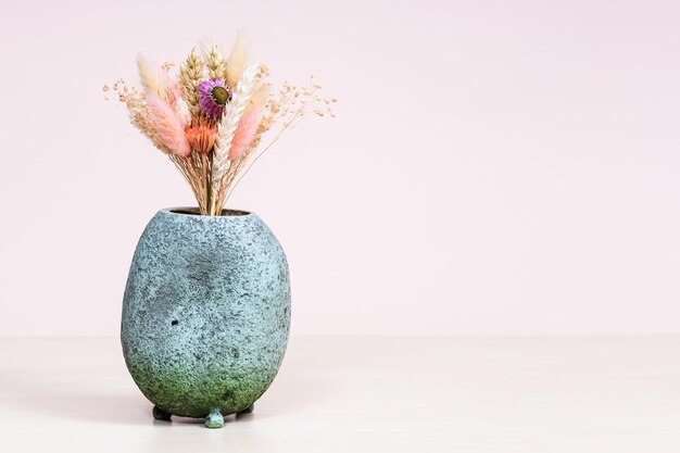 Vase with bouquet of dry flowers on table on pink