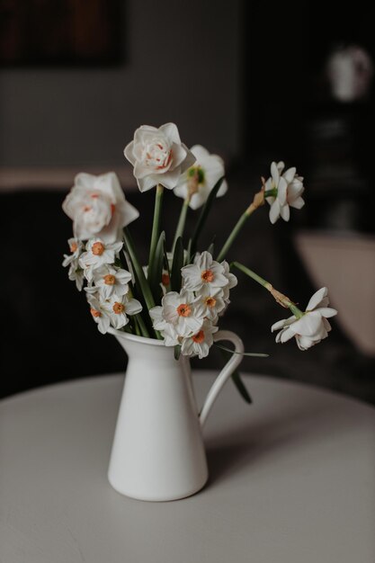 Vase with daffodils on table in light living room