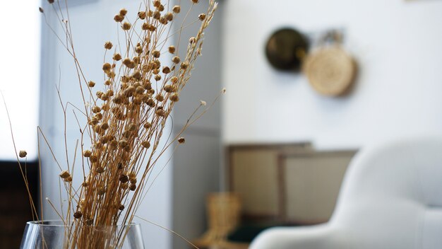 A vase with dry flowers on a table. Scandinavian classic room with wooden and white details, minimalistic interior design. Real photo. Cosy home.