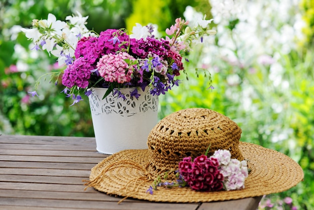 Vase with flowers and female hat