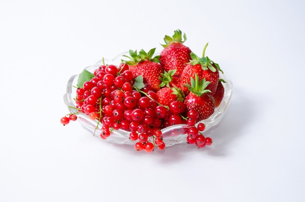 Foto vaso con frutti con fragole e ribes rosso su sfondo bianco, vista dall'alto.