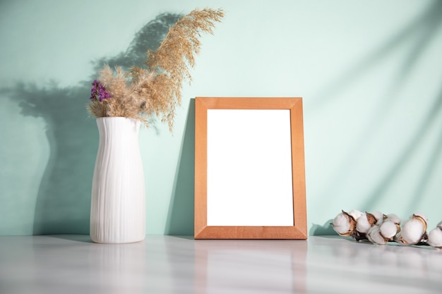 vase with grass and photo frame with cotton branch