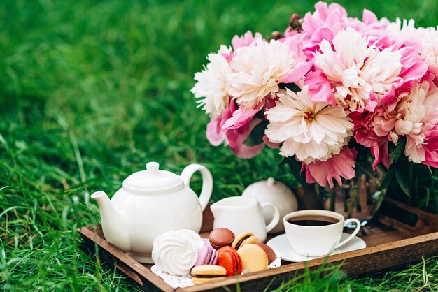 Un vaso con peonie una teiera e una tazza di tè su un vassoio