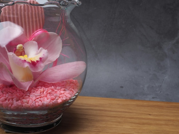 A vase with pink flowers and pink petals on a table.
