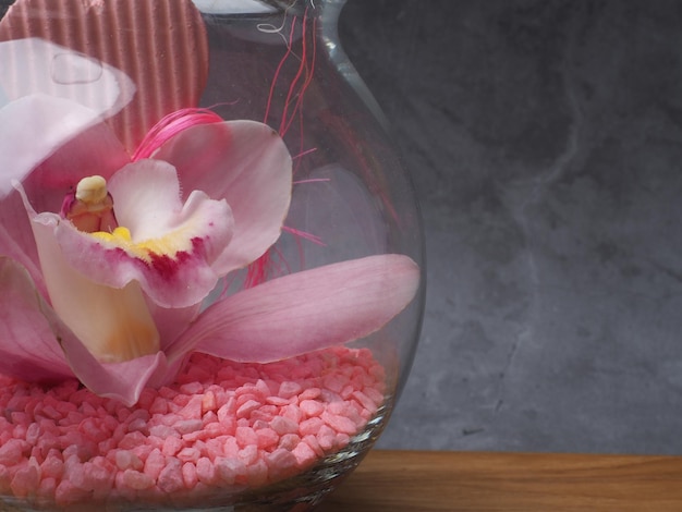 A vase with pink and yellow flowers and rocks in it.