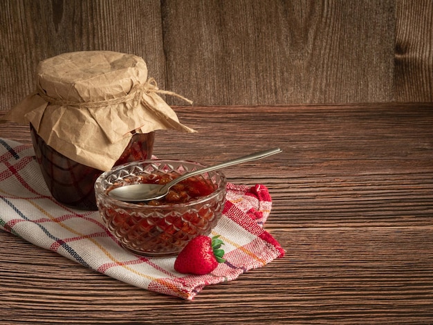 Photo a vase with strawberry jam a closed jar and fresh berries preserved for the winter