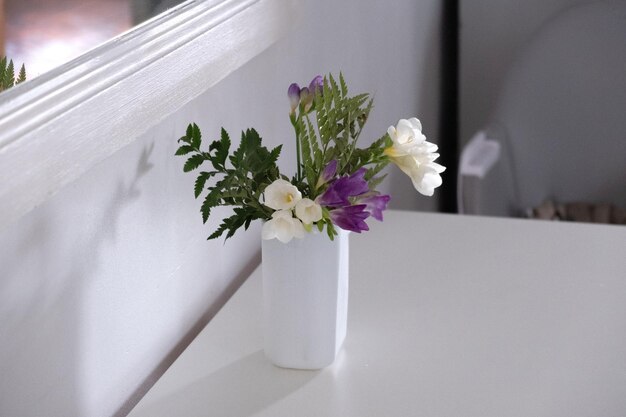 Foto vaso con fiori bianchi e viola sul tavolo