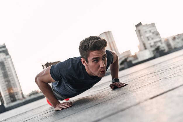 Vastbesloten om te winnen. jonge man in sportkleding die plankpositie houdt tijdens het sporten in de buitenlucht