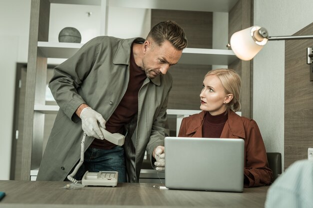 Foto vaste telefoon meenemen. blonde spion die alle rode outfit draagt die een virusprogramma op de laptop installeert met behulp van een usb-flashstation