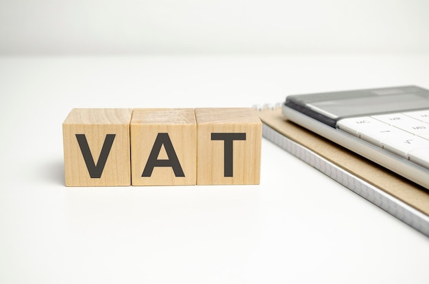 木製の背景にオフィス ツールと木製のブロックの VAT テキスト