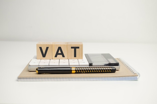 木製の背景にオフィス ツールと木製のブロックの VAT テキスト