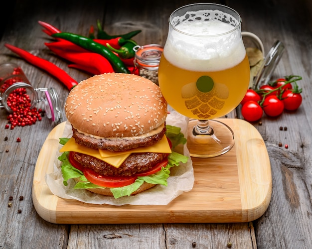 Veal burger with cheese and beer on wooden table