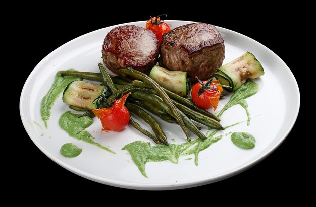 Veal medallions with green beans and Raclette cheese on dark background