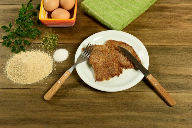 Veal milanese presented on the table with ingredients