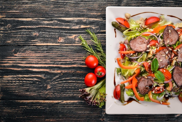 Фото Салат из телятины салат и свежие овощи на тарелке на деревянном фоне вид сверху свободное место для текста