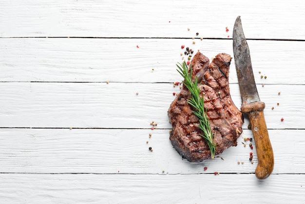 Veal steak on a bone on a white wooden background Free space for your text Top view