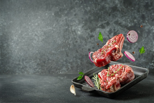 Veal steak flying over grill pan with ingredients on dark background. Copy space