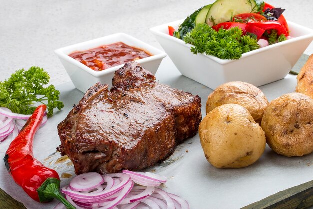 Veal steak with vegetable salad potatoes and sauce On a wooden board