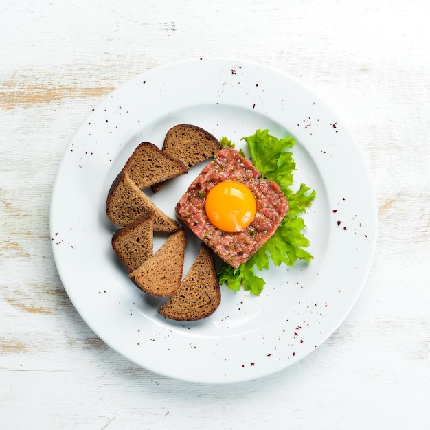 Veal tartar with egg yolk and black bread. Top view. Free space for your text.