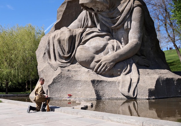 Foto vechter van het rode leger in de vorm van tijden van de tweede wereldoorlog met het machinegeweer bij een historisch monument op mamajev koergan in volgograd