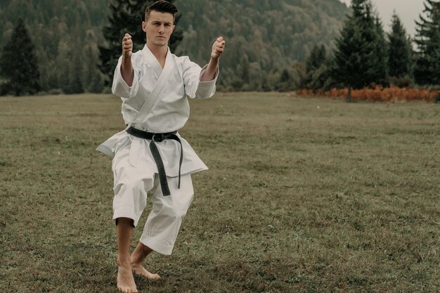 Vechtsport van karate een man in een kimono met zwarte gordeltreinen op de bergvrije ruimte