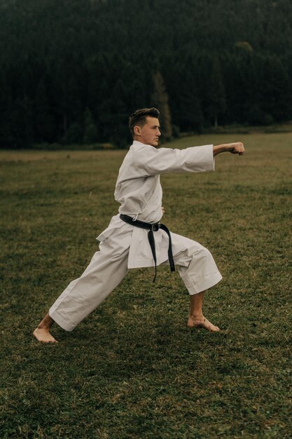 Vechtsport van karate een man in een kimono met zwarte gordeltreinen op de bergvrije ruimte