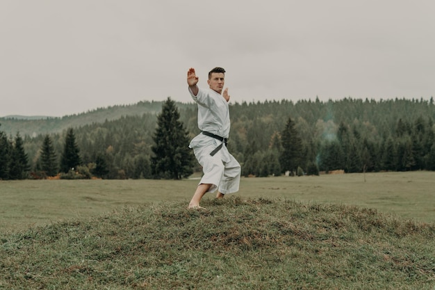 Vechtsport van karate een man in een kimono met zwarte gordeltreinen op de bergvrije ruimte