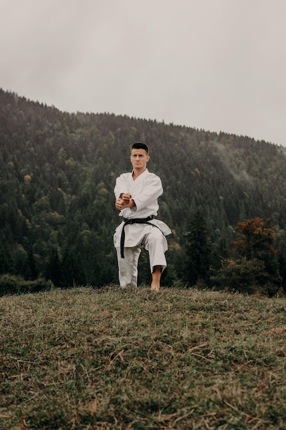 Foto vechtsport van karate een man in een kimono met zwarte gordeltreinen op de bergvrije ruimte