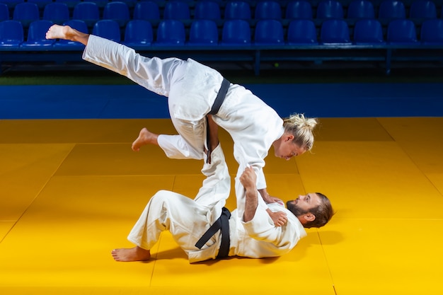 Vechtsporten. Sparen Portners. Sport man en vrouw in witte kimono trein judo gooit en vangt in de sporthal