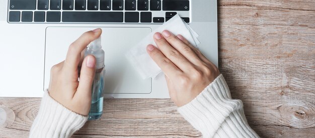 Veegt de vrouwen schoonmakende laptop met nat af en ontsmettingsmiddel