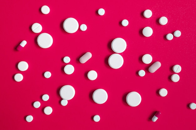 Veel antipyretische pillen of antibiotica op rode achtergrond voor een ontwerp over een medisch onderwerp
