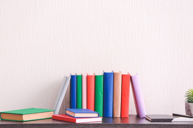 Veel boeken op tafel in de buurt van lichte muur