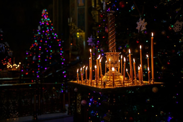 Veel brandende kaarsen staan in een gouden standaard in de kerk. Selectieve focus