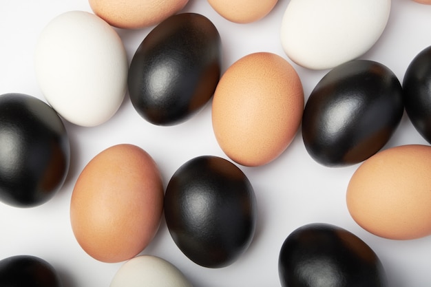 Veel eieren van verschillende kleuren op een witte achtergrond. Zwarte, witte en bruine kippeneieren.