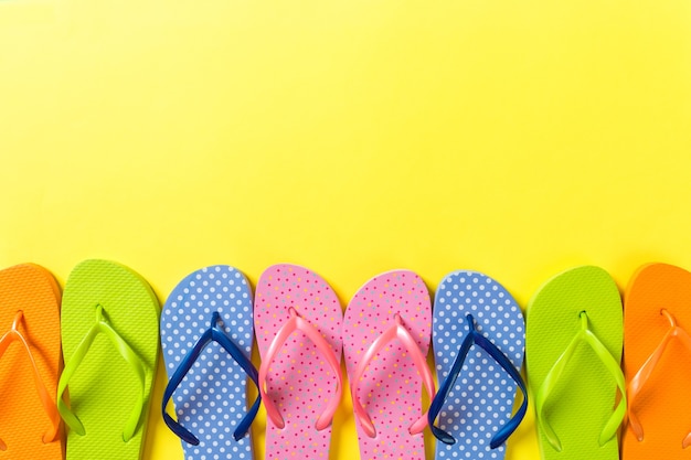 Veel flip flop gekleurde sandalen, zomervakantie op gekleurde achtergrond, kopieer ruimte bovenaanzicht.