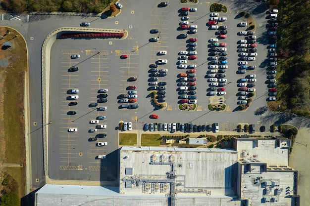 Veel geassocieerde auto's geparkeerd op een grote parkeerplaats voor het industriële fabrieksgebouw Manufactoring en wereldwijd industrieconcept