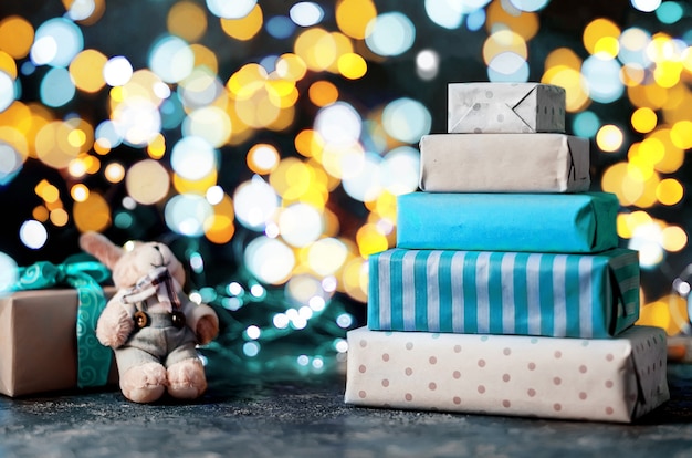 Veel geschenken in inpakpapier ambachtelijke en zelfgemaakte peperkoek huis, lichten bokeh op donkere achtergrond,