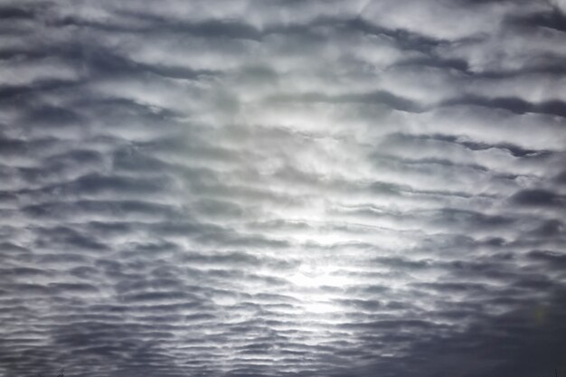 Veel getextureerde wolken in de blauwe lucht met zonlicht