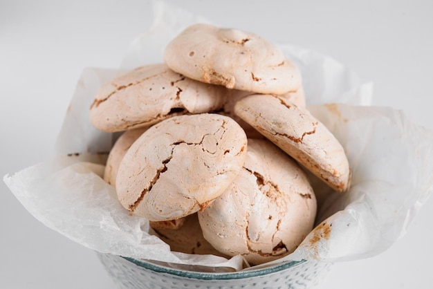 Veel heerlijke schuimgebakjes in een bord Meringue gevouwen in een dia in een blauw bord Meringue op een witte achtergrond