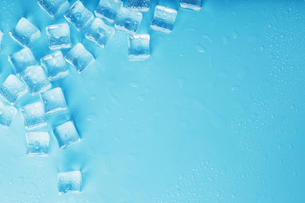 Veel ijsblokjes met waterdruppels verspreid op een blauwe achtergrond