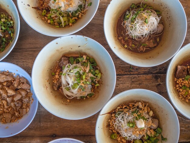 Veel kleine kommen Thaise noodle geserveerd op tafel.